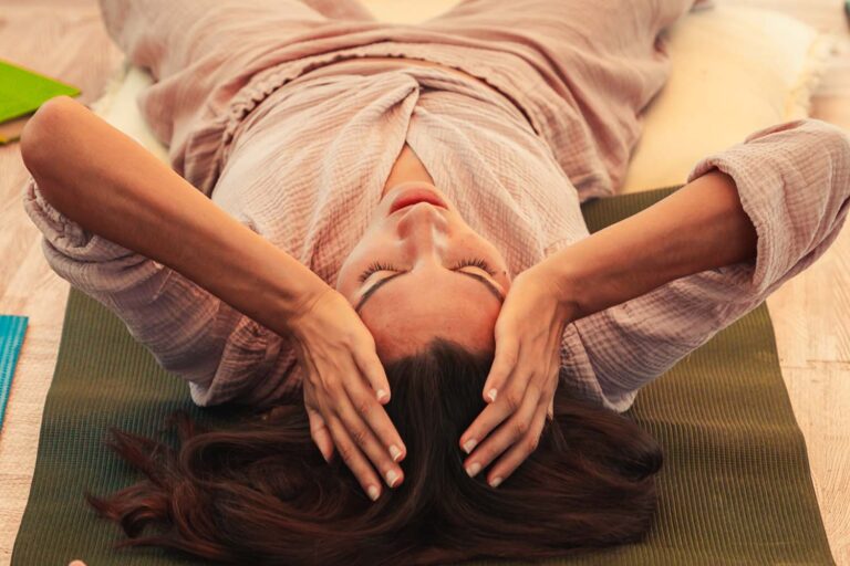 A woman on her mat, hands resting on her head